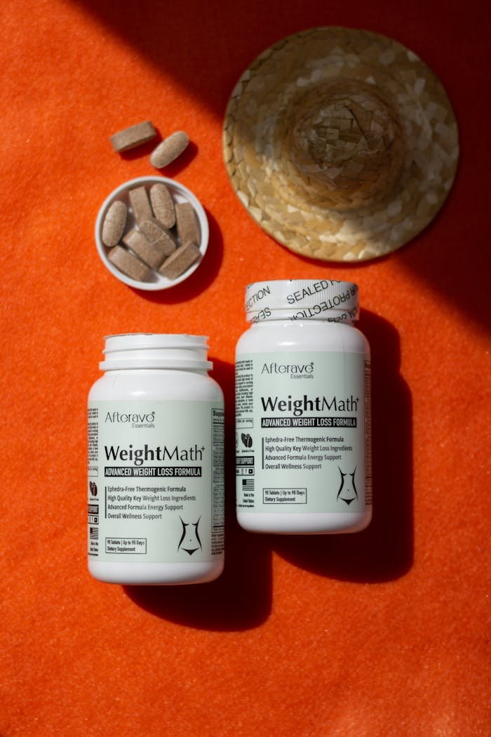 Weight loss supplements arranged on a vibrant orange backdrop with natural lighting.