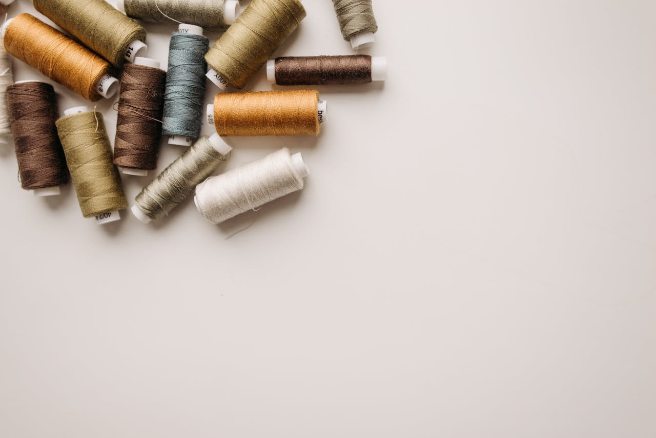 Top view of various colored spools of thread on a white background.
